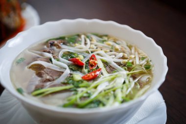 Geleneksel Vietnam pho Bo Pirinç Noodle ve haşlanmış Dana köfte çorbası kırmızı acı biber baharat beyaz kase hizmet verdi. Egzotik Asya restoran menü öğesi. Popüler Çince çorba portre