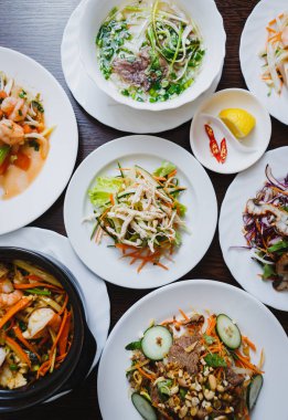 Üstten görünüm büyük Asya yemek menüsü'nde bulunan Vietnam restoranı. Genel gider bardak taze doğal salata ve pho kafede masada Beyaz tabaklar çorbaya bo. Baharatlar ve sos ile egzotik doğal gıda zevk