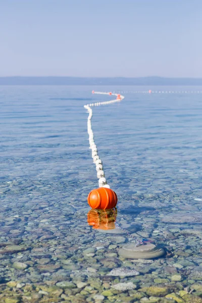 在亚得里亚海漂流的安全浮标 以防止水手和游泳者远离水中的危险岩石 在阳光下漂浮在公海海浪上的橙色浮标 — 图库照片