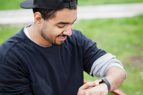 Sonriente Joven Negro Usando Reloj Inteligente Moda Sentado Parque Banco — Foto de Stock