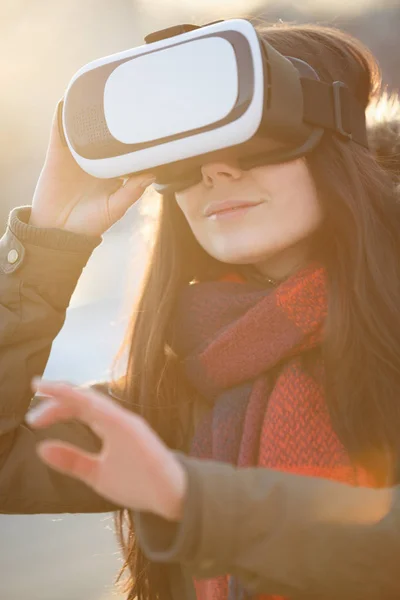 Young girl use cool new augmented reality glasses for mobile gaming applications outdoor in winter sunset.Use mobile games apps with innovative 3d headset.Modern virtual reality gamer gadget