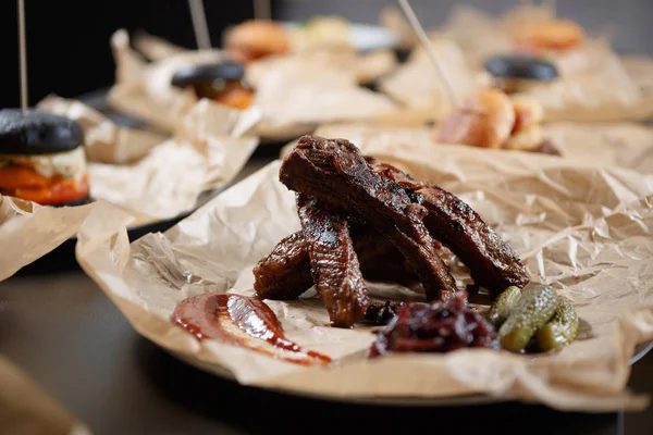 Delicious smoked ribs with sauce & pickled cucumber in fast food restaurant menu. Tasty bun unhealthy fat fried meat food close up.