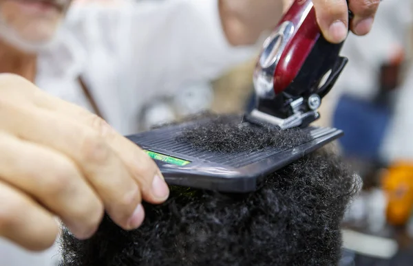 専門理髪店バーバー ショップ Studio でクリッパー ツール アフリカ縮毛をトリミングします 美容室サロンの黒人男性のクライアントの電気シェーバーを使って新しい髪形になります 男性美容治療コンセプト — ストック写真