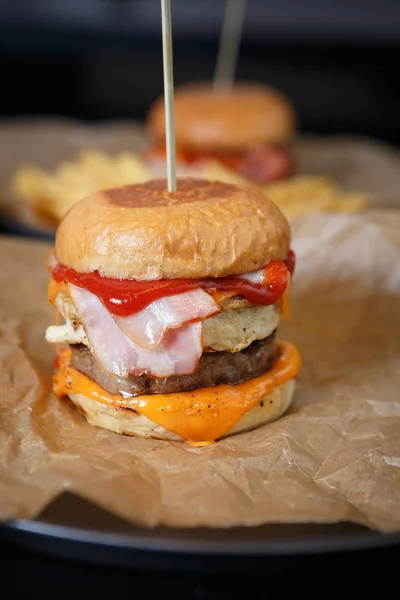 Big fat hamburger with beef meat & sauce served on decorative brown paper in fast food restaurant.Unhealthy buy tasty fat junk food in cafe menu.Smoker pork meat in fresh bun