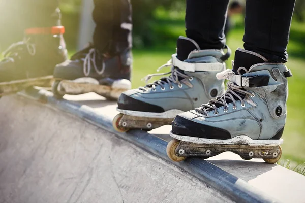 Açık skate Park beton rampa tepesinde duran agresif inline paten giymiş rollerbladers metrelik. Silindir bıçakları için hile ve biler giyen aşırı spor atlet