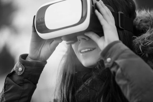 若い女性は 超クールなバーチャルリアリティ ガラス モバイル ゲーム用屋外で遊ぶ 革新的な のヘッドセットと携帯アプリを使用します トレンディな現実感使用でゲーマーのガジェットです ゴーグルを購入します — ストック写真