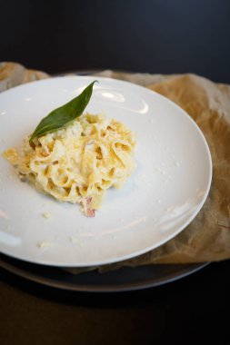 Fesleğen yaprak ve parmesan peyniri ile lezzetli İtalyan makarna yemek gurme restoranda beyaz tabakta servis. Yemek yemek için kafe menüsünü kapatın. Dikey portre vurdu