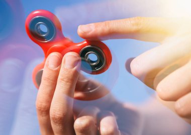 Serin yeni topluca spinner oyuncak. Modern iplik aygıt yatakları ile tutarak el. Döndürme ve denge ile bu serin yeni oyun keyfini çıkarın. Parlak bue gökyüzü arka plan