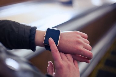 Yürüyen merdiven metro sürme sırasında akıllı saatini kullanan kadın. Bu yeni becerikli alet her zaman internet ve sosyal medya ağları ile istediğiniz yerden bağlı kalmak sağlar.