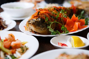 Lezzetli kızarmış karp balık taze sebze ve baharat soslu pişmiş. Yakın çekim, Vietnam restoranı içinde pişmiş deniz ürünleri odaklanmak. Geleneksel Asya yemeği beyaz tabak salata ile servis