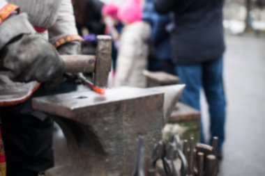 Shrovetide pagan Festivali kutlama. Rus Maslennica bahar tatil karnaval arka plan. Zemin için bulanık dövmesi ürünler. Siyah smith ile çekiç örs üzerinde çalışır.