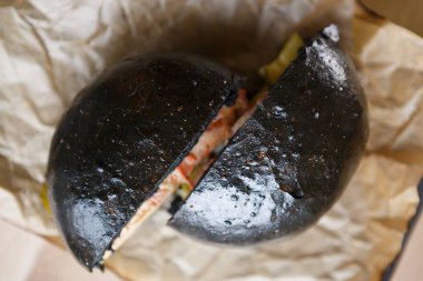 Et restoran menü öğesi havai shot. Büyük siyah Burger yarıya içine kesilmiş kağıt plaka üzerinde servis