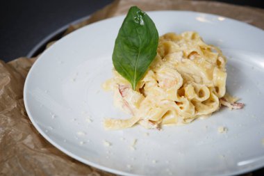 Fesleğen yaprak ve parmesan peyniri ile lezzetli İtalyan makarna yemek gurme restoranda beyaz tabakta servis. Yiyecek çanak yakın çekim için kafeterya menüsü