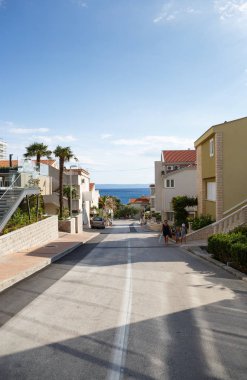 Makarska, Hırvatistan-17 Haziran 2017: şehir yolu plaja yol açar. Arka planda derin mavi su ile güzel Adriyatik Denizi. Popüler turistik bölgenin Sokağı 
