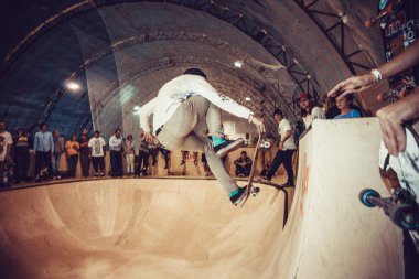 MOSCOW - 6 SEPTEMBER,2015: Young skateboarder guy do air grab trick on skateboard in indoor skate park during contest clipart