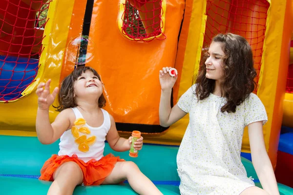 Two Cute Young Sisters Playing Bubble Wand Bouncing Castle Background — Stock Photo, Image