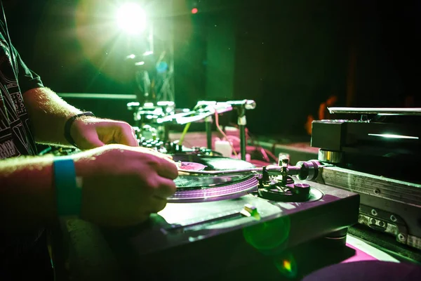 KIEV-4 JULY,2018: Nightclub party dj plays music with retro Turntables. Club DJ Panchez put needle on vinyl record at drum and bass party in bright green stage lights