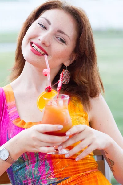 Beautiful young lady enjoying her fresh cocktail sitting in a restaurant outdoors