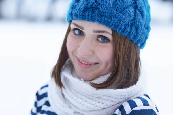有趣的年轻的姜女孩做脸 模糊背景 美丽的年轻白人女孩在温暖的蓝色针织冬帽在户外摆姿势 冬季模糊背景 将文本放在模糊背景上 — 图库照片