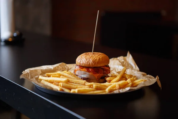 Huge fat burger in fast food restaurant menu.Delicious big tasty hamburger with beef meat cutlet, tomato ketchup sauce & burned cheese served on plate in fastfood cafe