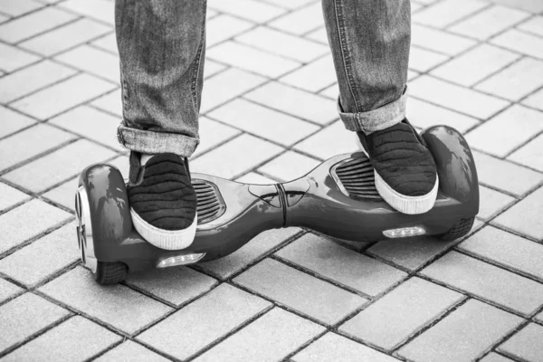 Feet of a girl riding on modern red electric mini segway or hover board scooter. Trending new transportation technology that is so much fun and easy to ride and produces no air pollution to the atmosphere. Close up on model legs and gadget.