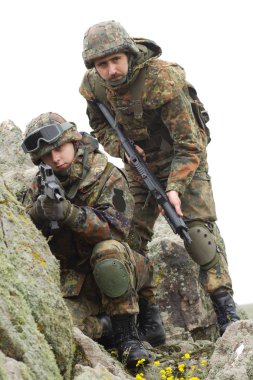 Askeri yardım. Ordu takım çalışması. Savaş üniforması içinde Ukraynalı ordunun kamuflajında silahlı askerler. Soldier takım üyesi tırmanmaya kaya açık yardımcı olur. Savaş Doğu Ukrayna. Heavy mühimmat, otomatik tüfek