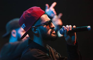 Moskova - 20 Ekim, 2016: Rap şarkıcı şarkı sahne gece kulübü. Hip hop müzik sanatçı şarkı mikrofon sahnede. Rapçi parlak konser aydınlatma.