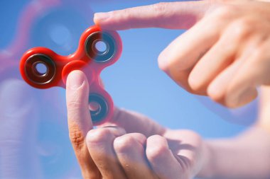 Serin yeni topluca spinner oyuncak. Kadın oyun modern iplik cihazı ile. Rulman ortada dönen süper trendy bu becerikli alet ile oynarken zevk. Parlak mavi gökyüzü arka plan