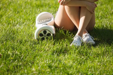 Elektrikli mini vurgulu kurulu scooter üzerinde çim yeşil park kadın var. Eko şehir ulaşım pille, üretmek için atmosfer hava kirliliği