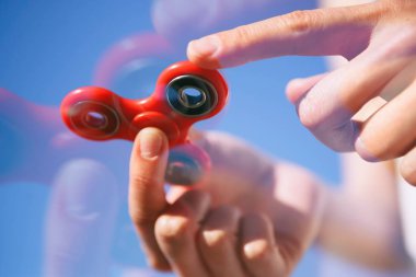 Serin yeni topluca spinner oyuncak. Modern iplik aygıt yatakları ile tutarak el. Döndürme ve denge ile bu serin yeni oyun keyfini çıkarın. Parlak bue gökyüzü arka plan