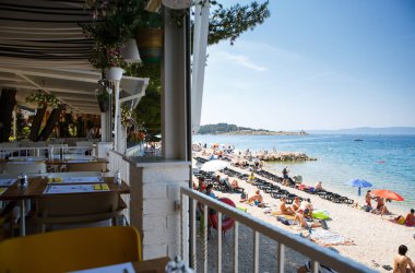 Makarska, Hırvatistan-16 Haziran 2017: Adriyatik Denizi plajında popüler turist alanında Plaj restoranı. Sahil ve kristal berraklığında mavi suda güzel manzaralı rahat yazlık kafe