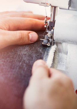 Terzi bir dikiş makinesi ile üzerinde elinde bir iğne odaklanmak kadar kapatın