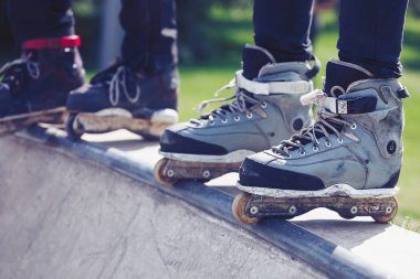 Açık skate Park beton rampa tepesinde duran agresif inline paten giymiş rollerbladers metrelik. Silindir bıçakları için hile ve biler giyen aşırı spor atlet