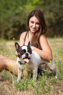 genç esmer kız parkta onun sağlıklı genç bulldog ile oynarken