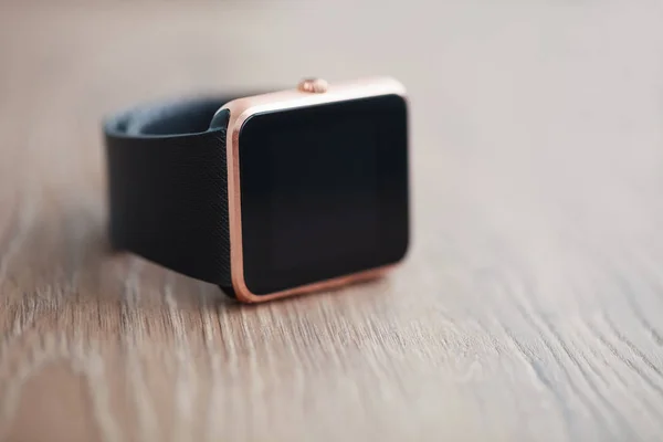 Modern smart watches on wooden background. Trendy new technology that let you always stay connected to internet and social media. Place text or app icon on blank black screen. Macro close up