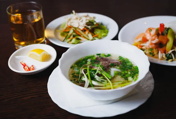 エキゾチックなレストランでのディナーにおいしいベトナム料理 美味しいフォーをお楽しみくださいボー スープ 天然植物成分のサラダ カフェのテーブルでアジア ビジネス ランチ メニュー — ストック写真