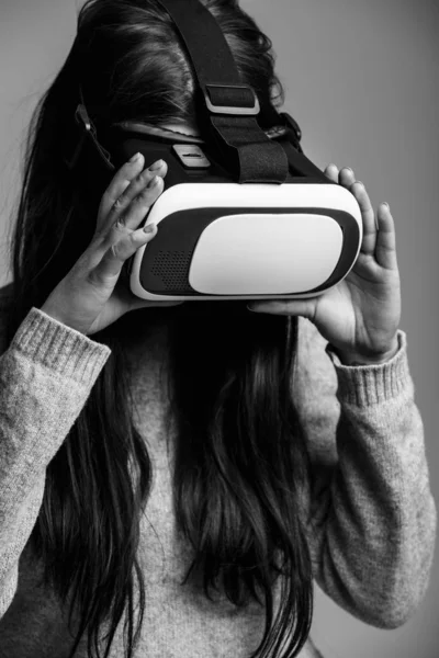 Studio portrait of pretty young female using new virtual reality glasses for mobile gamer applications.Girl use mobile games apps with innovative 3d vr headset.Trendy augmented reality gadget in use