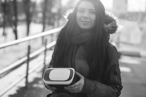 Young woman walk outdoor with new virtual reality glasses for mobile gaming apps.Use mobile games applications on the go.Modern augmented reality gamer gadget.Pretty geek girl with innovative gadgets