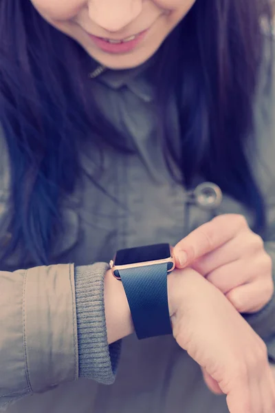 Smiling young woman using her trendy smart watch. This new gadget lets you always stay connected to internet and social media networks from anywhere you want.