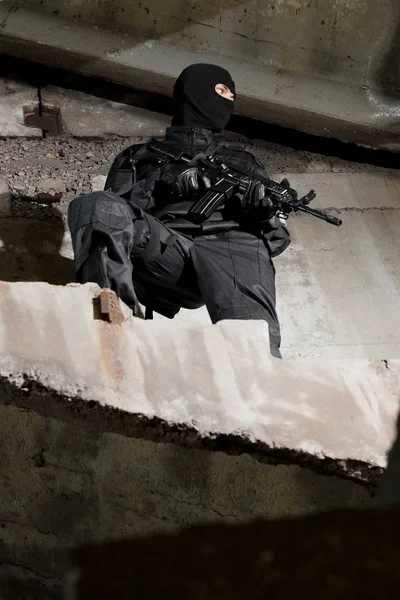 ライフル立っている階段の上を保持している黒の制服を着た男 — ストック写真