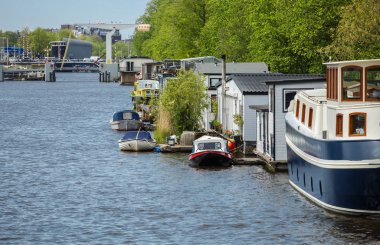 Amsterdam,Hollanda-27 Nisan,2019: Amsterdam eski şehir bölgesinin merkezinde Amstel Nehri Kanalı. Merkezinde köprü ile geniş nehir bankaları, kıyıda eski Hollanda evleri