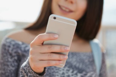 Mutlu gülümseyen genç esmer kızın elinde büyük gümüş akıllı telefon. Modern Gadget'ı fotoğraf çekmek ve internet'te gezinmek için