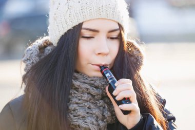 Sevimli Genç beyaz kız vape dışında. Vaping ejuice veya eliquid için popüler elektronik aygıtı. Modern taşınabilir elektronik sigara kullanılıyor. E-cig Buharlaştırıcı aygıt olan kadın