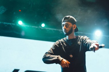 Moskova - 20 Ekim, 2016: Rap şarkıcı şarkı sahne gece kulübü. Hip hop müzik sanatçı şarkı mikrofon sahnede. Rapçi parlak konser aydınlatma.