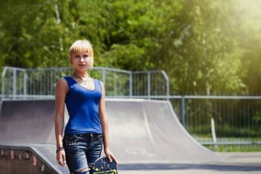 Punk patenci kız yırtık kot açık bir skatepark içinde onun kaykay üzerinde hazır 