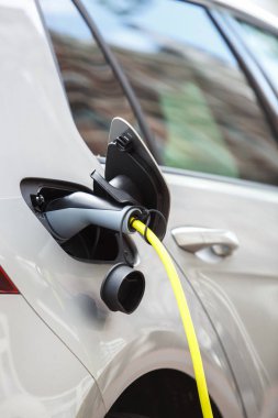 Modern elektrikli otomobil park yerinde şehrin gün sokak üzerinde güç kablosu ile şarj. Yeni temiz enerji kavramı. Elektronik motor sıfır kirlilik araçla. Otomatik İstasyonu şarj