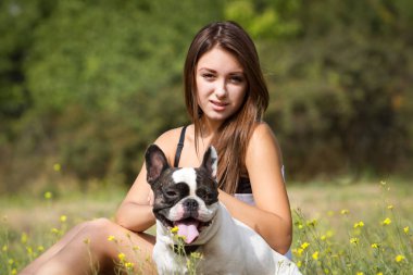 genç esmer kız parkta onun sağlıklı genç bulldog ile oynarken