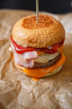Lezzetli, büyük, çift katlı hamburger. Amerikan fast food restoranı menüsü. Soslu ızgara büyük hamburger, kahverengi kağıtta servis edilen domuz peyniri.