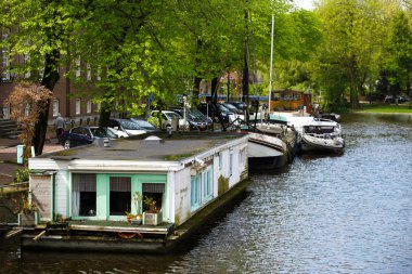 Amsterdam,Hollanda-27 Nisan,2019: Amsterdam eski şehir bölgesinin merkezinde Amstel Nehri Kanalı. Merkezinde köprü ile geniş nehir bankaları, kıyıda eski Hollanda evleri