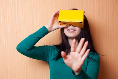 Çekici genç kız karton sanal artırılmış gerçeklik kulaklık ile vr video oyunu oynuyor. Popüler teknoloji, hipster renkleri. Akıllı telefonda mobil oyun için Vr gözlükler. Pretty genç oyuncu kız oyna. 